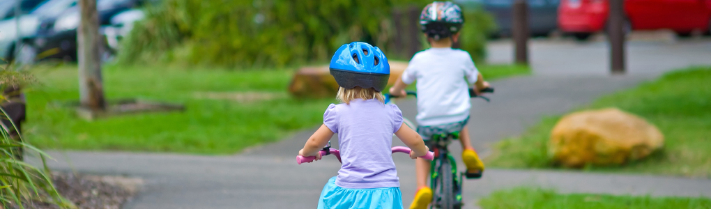 Two children safely riding their bikes.